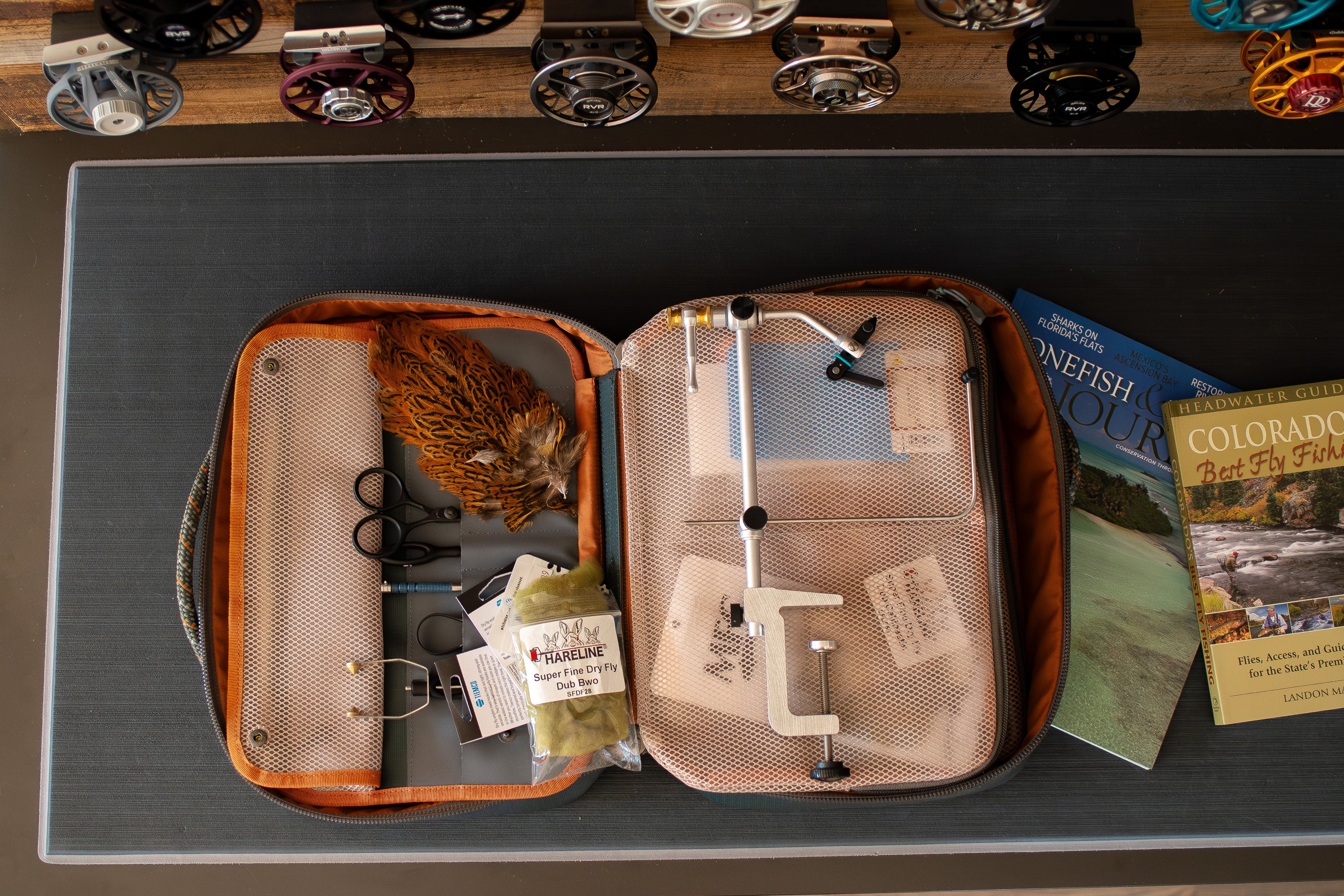 Open fishing tackle fly tying box with tools and accessories on a table