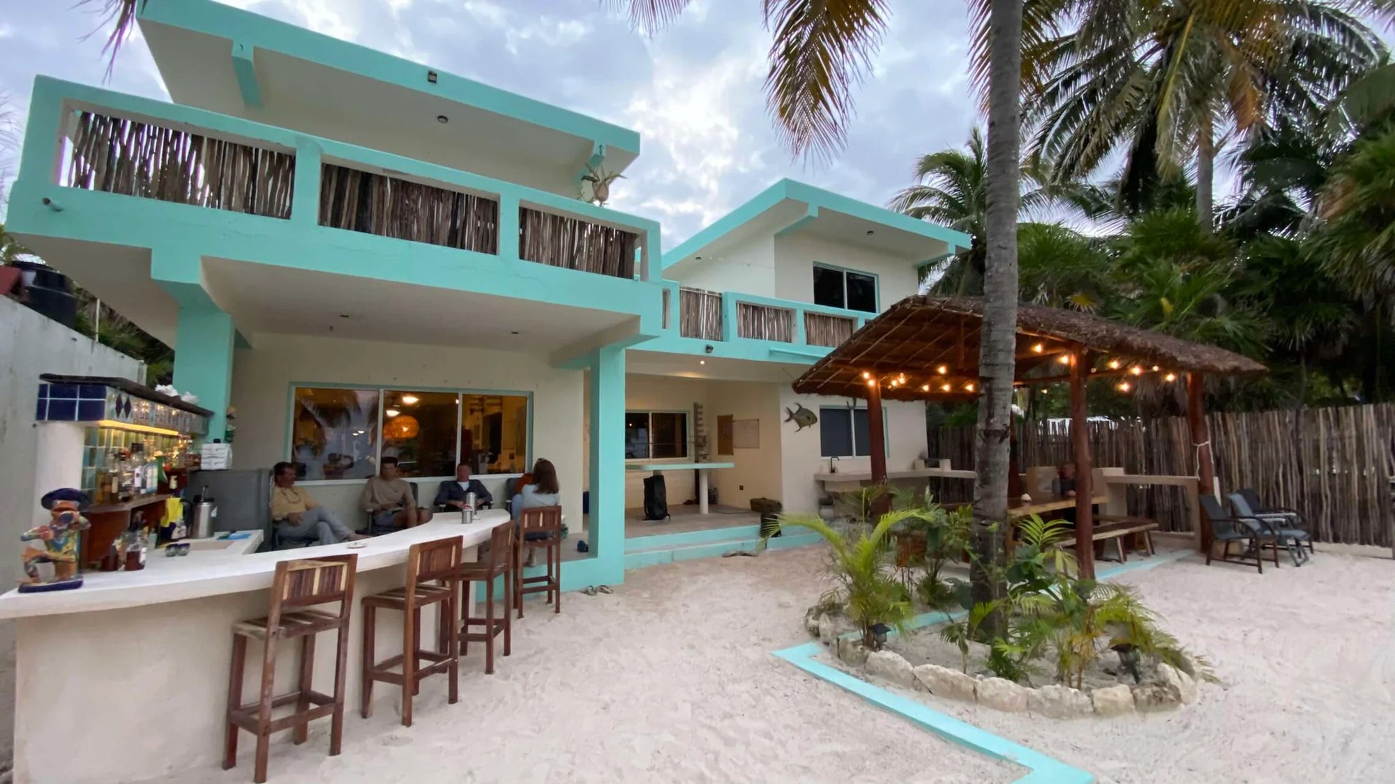 Beachfront restaurant with turquoise building and outdoor seating area.