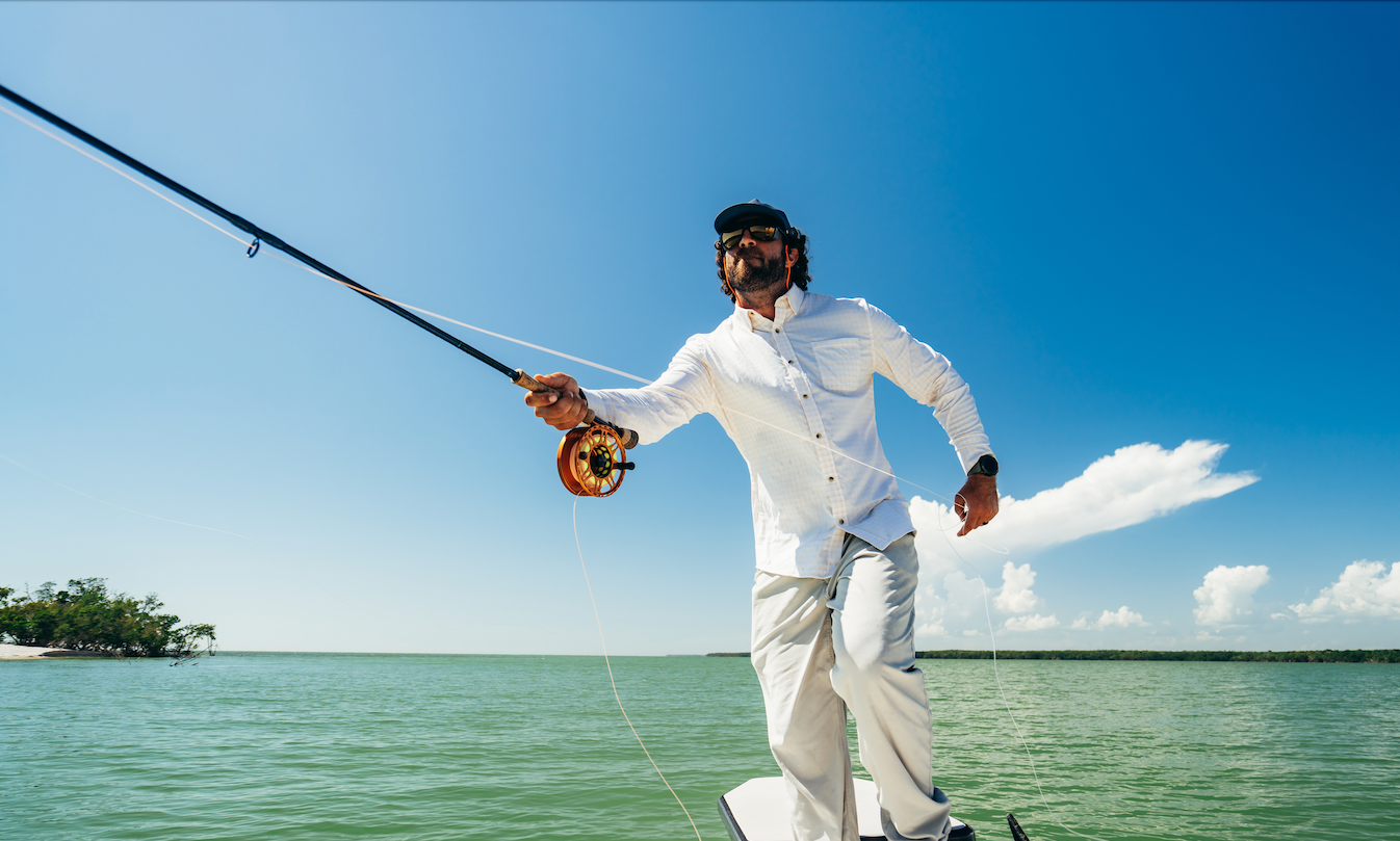 Man fishing on a boat with a clear blue sky and calm water background