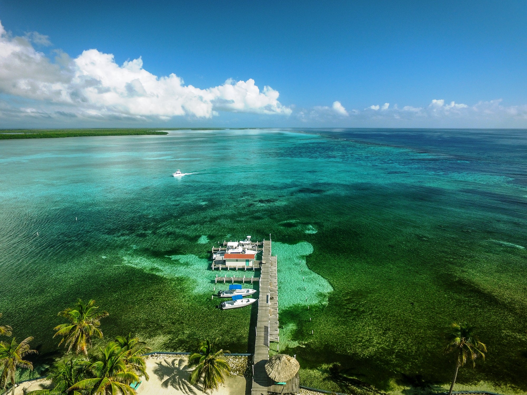 Aerial view of a dock with boats in clear turquoise water under a blue sky.